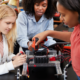 STEM education grants; female students and teacher work on tech project in classroom