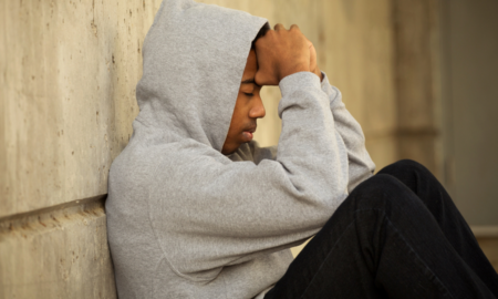 Specialized Case Management for Young Adults in extended foster care report; troubled youth in hoody sitting against wall