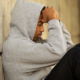 Specialized Case Management for Young Adults in extended foster care report; troubled youth in hoody sitting against wall