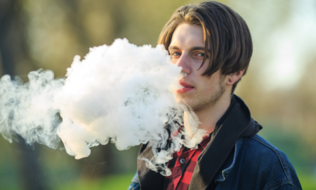 tobacco product use among middle and high school students report; male high school student blowing out cloud of vapor