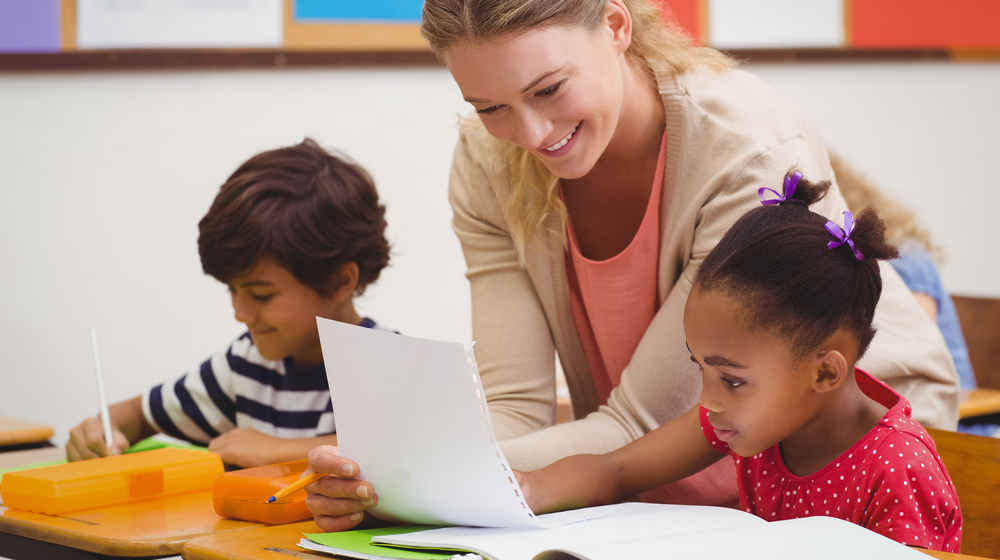 teacher professional development, early childhood educator grants; female teacher smiling while teaching young students