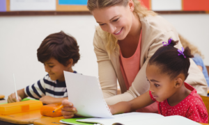 teacher professional development, early childhood educator grants; female teacher smiling while teaching young students