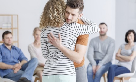 substance abuse treatment: two people hugging in a group therapy session