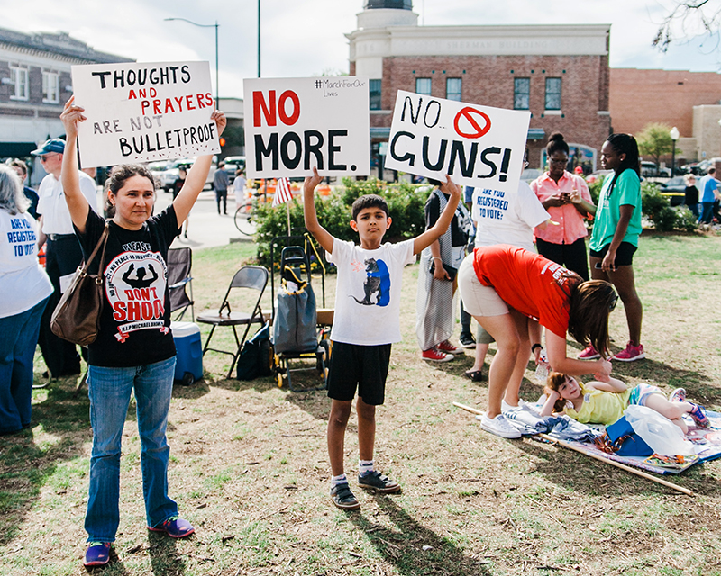 Sandy Hook: Woman and little boy hold protest signs about gun violence.