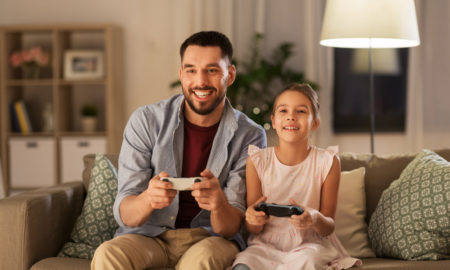 relationships: happy man and little girl with gamepads playing video game at home