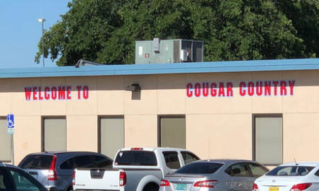 Las Cruces: Low brick building with sign Welcome to Cougar Country; cars parked next to it