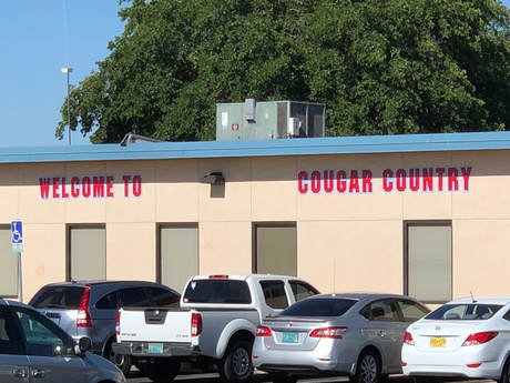 Las Cruces: Low brick building with sign Welcome to Cougar Country; cars parked next to it