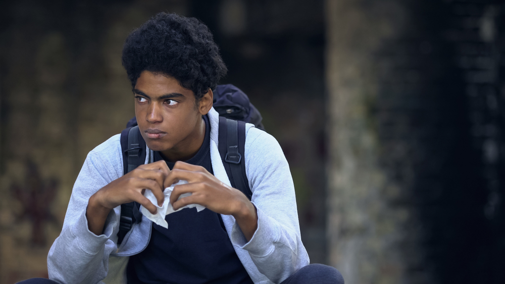 threat assessment: Thoughtful black student holding snack outdoors