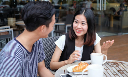 trafficking: Close-up of couple talking at cafe table with coffee cups and dessert