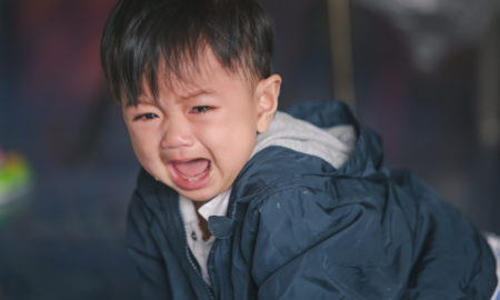 foster care: A young baby having a fit on the ground crying.