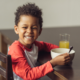 Strategies and Challenges in feeding OST students reports; happy african-american child with bowl of food and drink