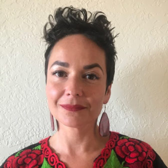 homelessness: Marisol Atkins (headshot), consultant for Northern New Mexico Youth Homelessness Demonstration Project, smiling woman with short black hair, earrings and red top