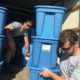 jobs programs: 2 young men pick up big blue rubber containers from truck
