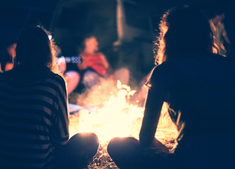 crip camp: People sit at night around a bright bonfire.