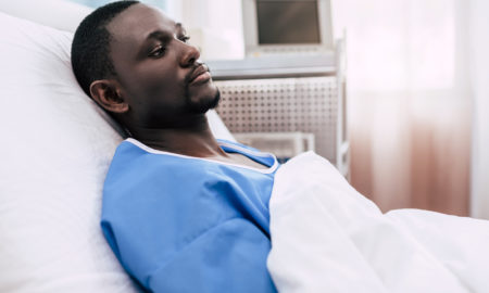 gun violence: side view of pensive african american man lying in hospital bed