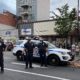 3 New York Police officers stand near squad car in middle of street.