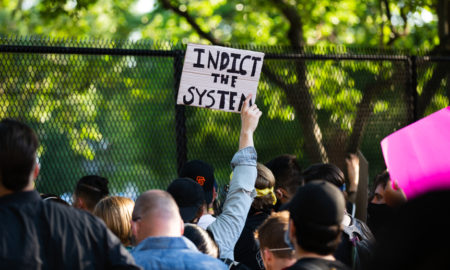 police: Protestor holds sign that says indict the system