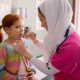 Community needs, healthcare and science education grants; female doctor with hijab treating young girl with red hair