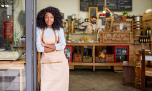 Low-Income Community Minority-Owned Business Support grants; young black woman stands at the front of her shop