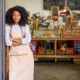 Low-Income Community Minority-Owned Business Support grants; young black woman stands at the front of her shop