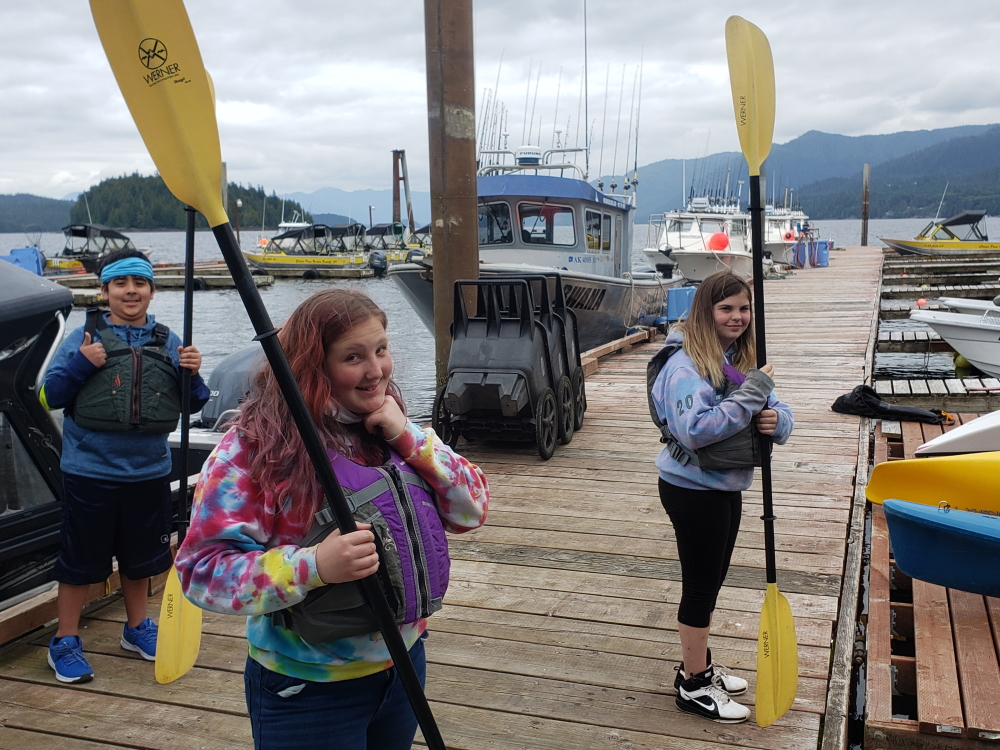 Alaska: 3 kids hold kayak paddles on pier.