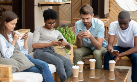 4 young people sitting on couch looking at phones
