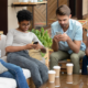 4 young people sitting on couch looking at phones
