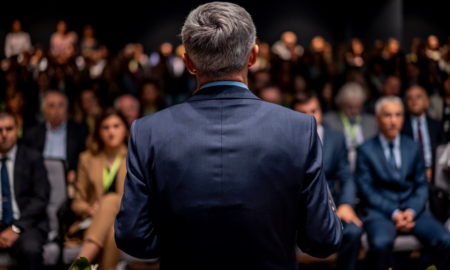 Man in suit making a speech in front of a big audience