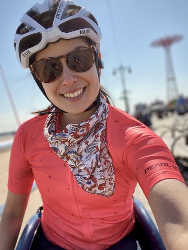 exercise: smiling woman wearing bike helmet, sunglasses, orange workout shirt, paisley scarf