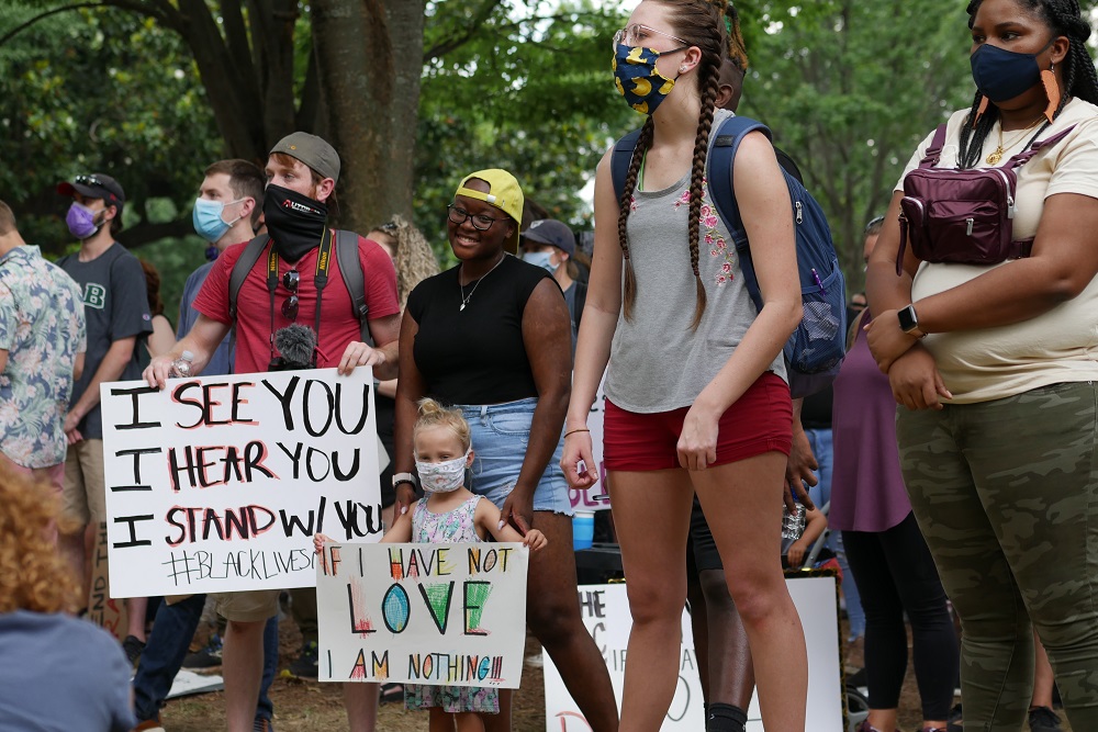 defunding: People in masks, including little girl, stand still, hold up signs Tags: targeting gun violence project, gun violence, police, Alabama, Birmingham, racism, defunding