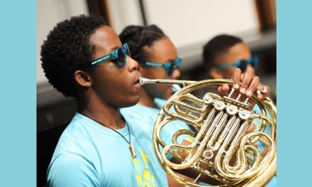 Miami: Line of students play instruments wearing blue sunglasses, uniform T-shirts