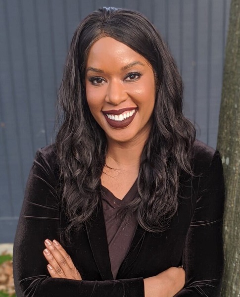 gun violence: Amber Goodwin (headshot), executive director of Community Justice Action Fund, smiling woman with long brown hair, brown velvet jacket, brown top