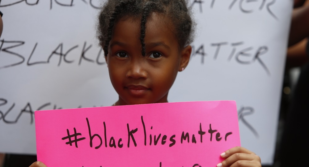 Child holds black lives matter sign