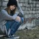 sex trafficking: Homeless teenage girl sitting near brick wall outdoors