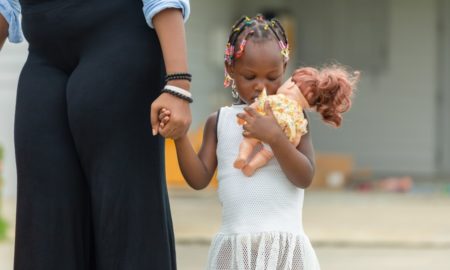 normal: Woman holds hand of sad little girl hugging doll