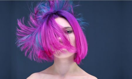 neurodivergence: young woman with pink and purple hair color in close-up on a colorful background with fluttering hair.