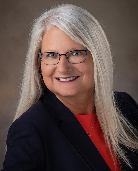 fundraising: Beverlee Wenzel (headshot), executive director of ROCK Center for Youth Development, smiling woman with long graying blonde hair, glasses, red top, black jacket