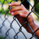 expand use of diversion for juvenile justice system report; hand of youth on detention center fence