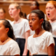 arts: Children singing in chorus wearing white shirts