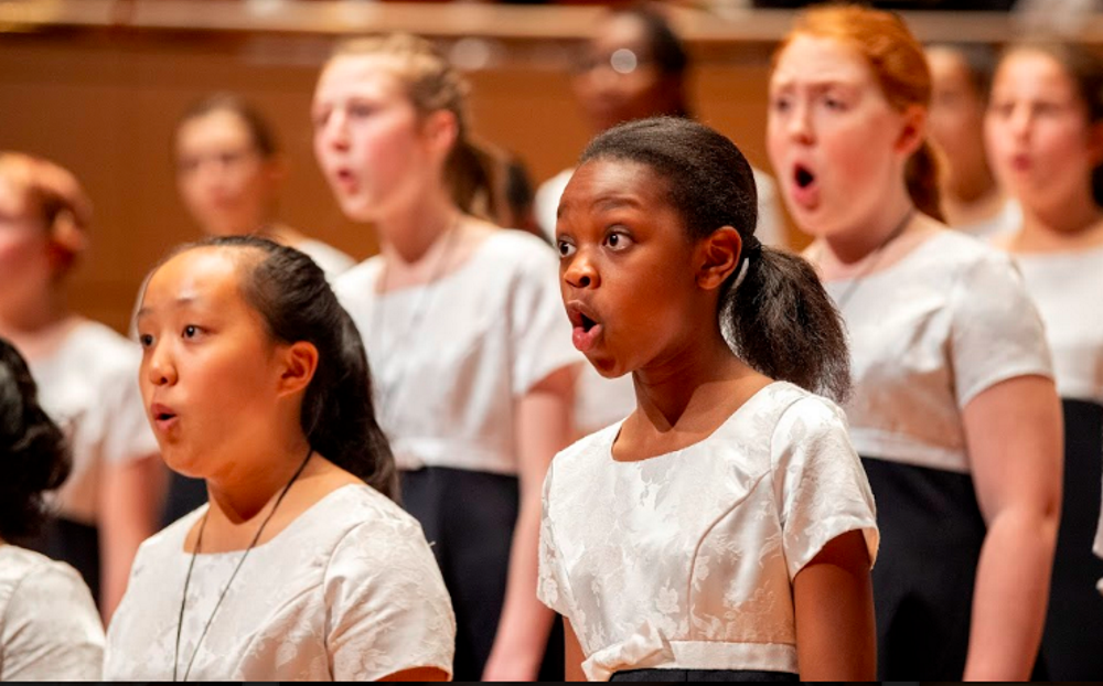 arts: Children singing in chorus wearing white shirts