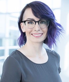 gun violence: Jennifer Peck (headshot), assistant professor at University of Central Florida, smiling woman with purple hair, glasses, black top