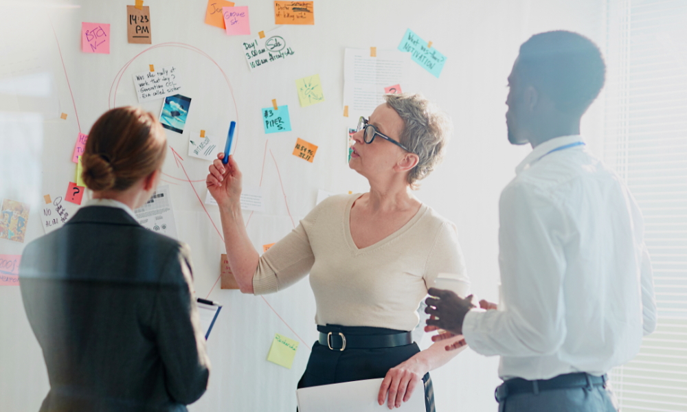 homelessness: 2 women, 1 man discuss notes on whiteboard