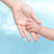 children’s advocate: Adult holds child’s hand on soft blue background