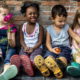 Group of smiling small kids sit against brick wall