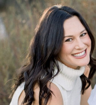 Ally Barron (headshot), development and communications officer of Hope and Heal Fund, smiling woman with long dark hair wearing sleeveless white turtleneck