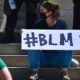 protests: White woman sits on steps holding #blm sign