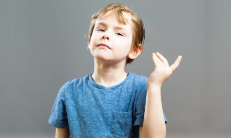 story: little boy in blue shirt gestures against gray background