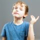 story: little boy in blue shirt gestures against gray background