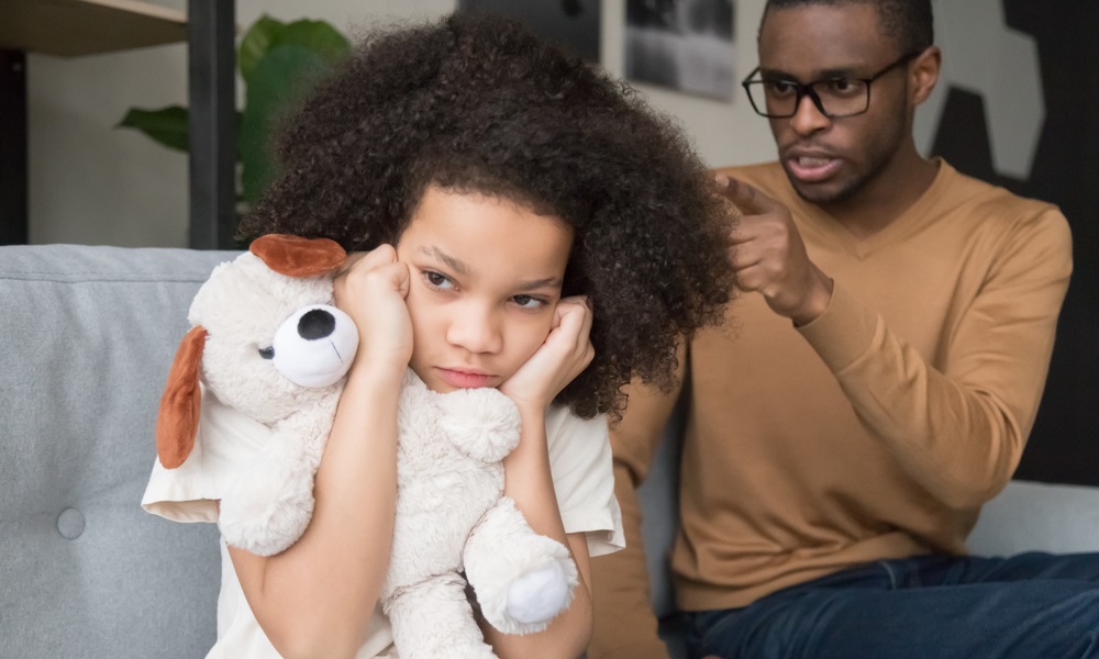 child abuse: Young Black girl closing ears ignoring angry strict Black dad scolding