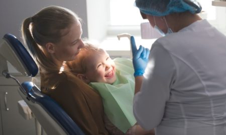 Little girl with mommy in dentist room - conversation with doctor; maternal and child oral health grants